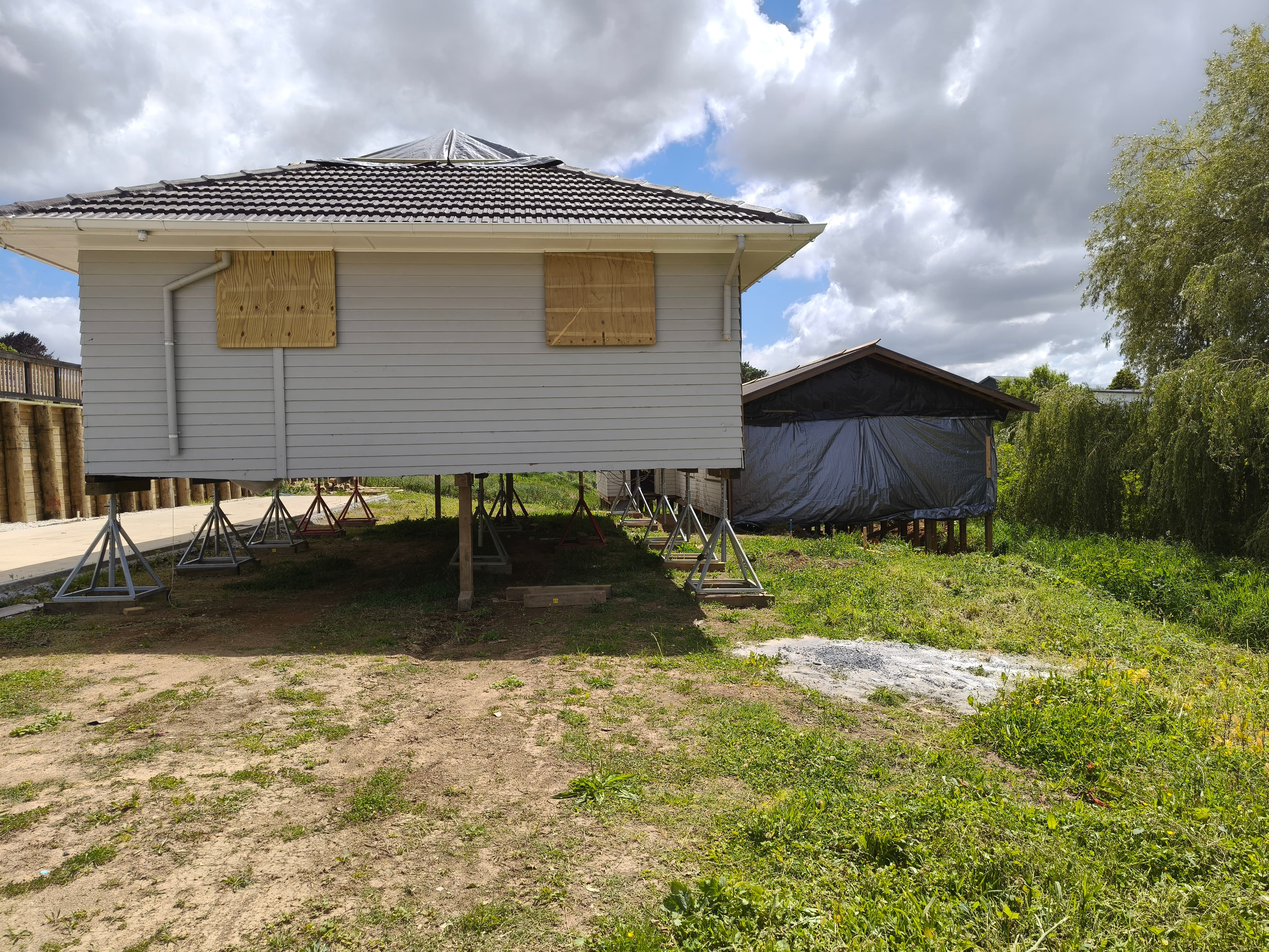 Relocatable dwelling raised on temporary screw jacks and steel stands on a new site before permanent foundations are completed.